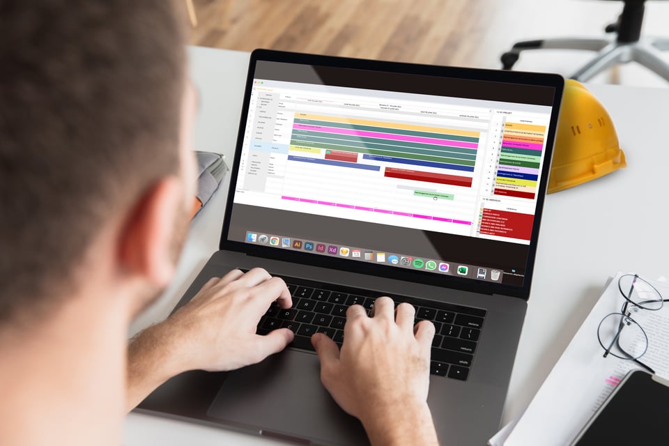 Un homme sur son ordinateur portable en train de travailler sur le logiciel visual planning