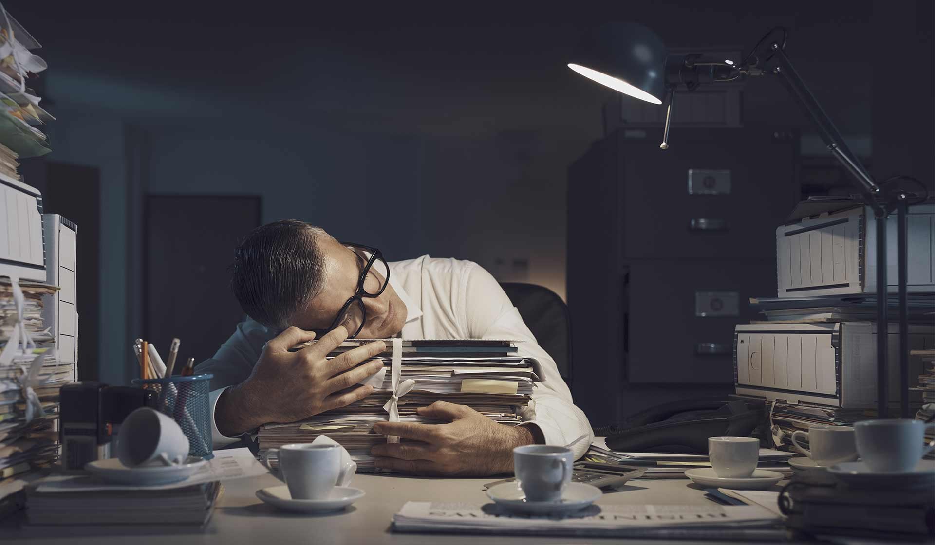 Müder Mitarbeiter schläft am Schreibtisch