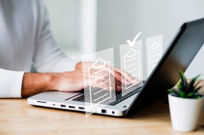 un comptable sur son ordinateur sur lequel apparait des icones de document avec le symbole validé