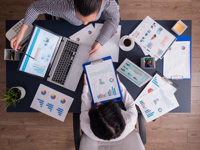 deux comptable vue de dessus qui analyse des graphiques sur du papier et un ordinateur